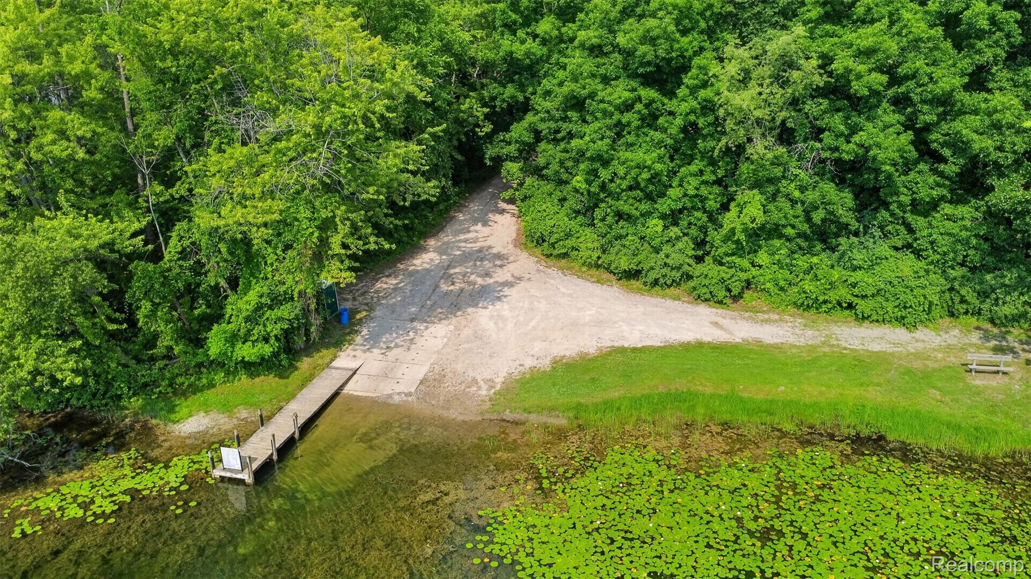 5977 Anglers Road Ortonville, MI 48462 - Photo 50 of 63 Waterfront access featuring a wooden dock, gravel shore, and surrounding mature trees