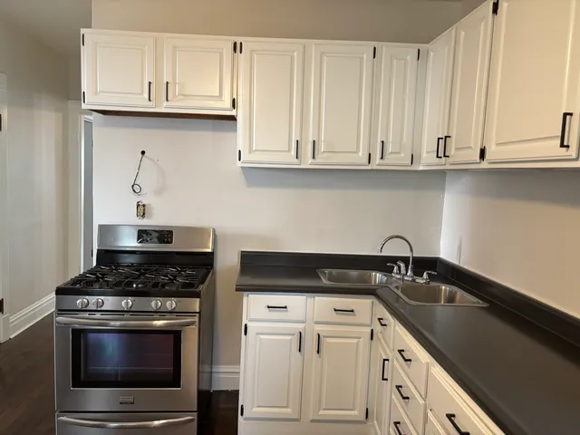 a kitchen with white cabinets and a stove with a sink