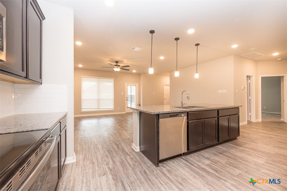 113 Lazy Lizzy Road Jarrell, TX 76537 - Photo 11 of 29 a open kitchen with stainless steel appliances granite countertop a large stove a sink dishwasher and a refrigerator with wooden floor