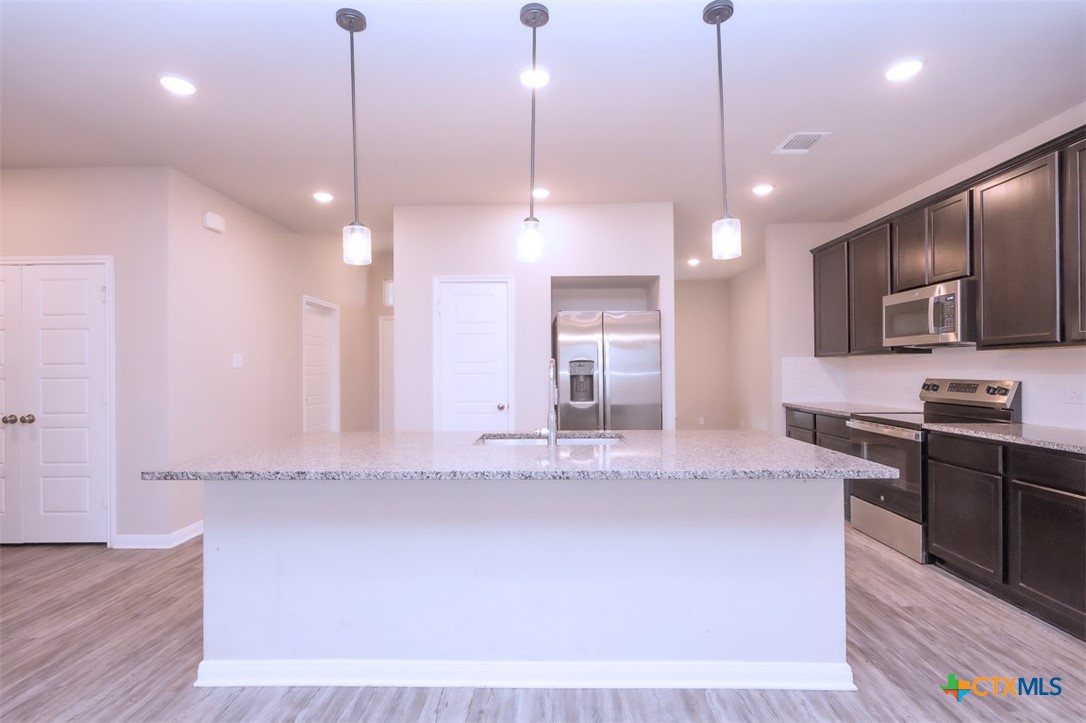 113 Lazy Lizzy Road Jarrell, TX 76537 - Photo 12 of 29 a large kitchen with kitchen island granite countertop a stove a sink a center island a refrigerator and a fireplace