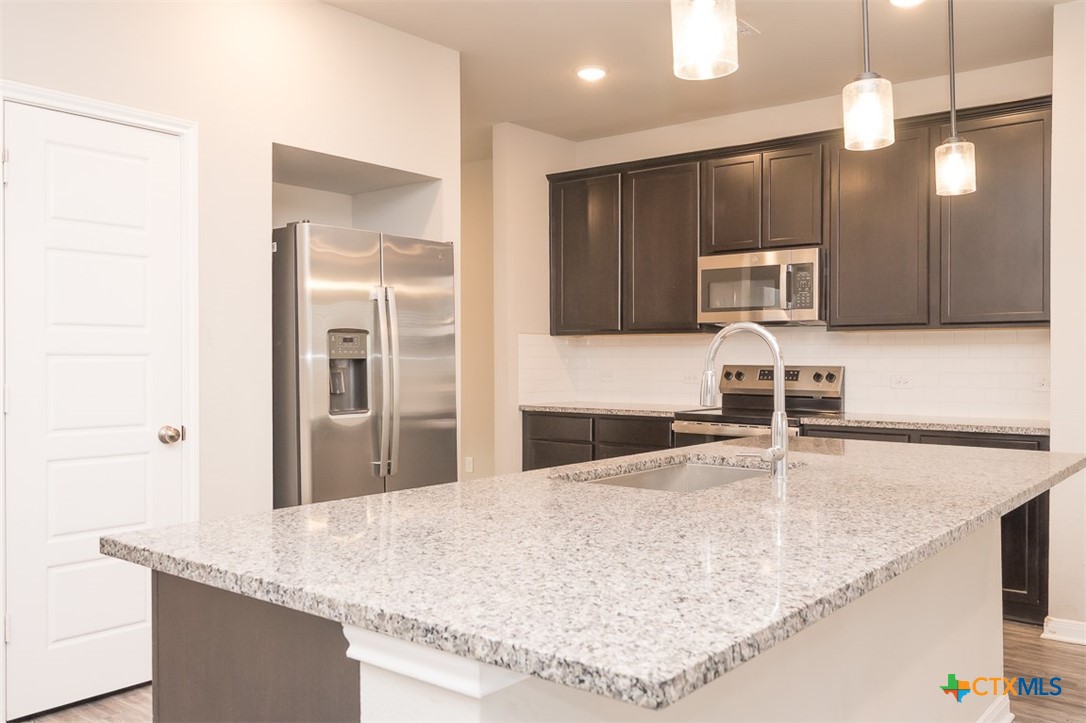 113 Lazy Lizzy Road Jarrell, TX 76537 - Photo 4 of 29 a kitchen with kitchen island a counter top a sink and a stove