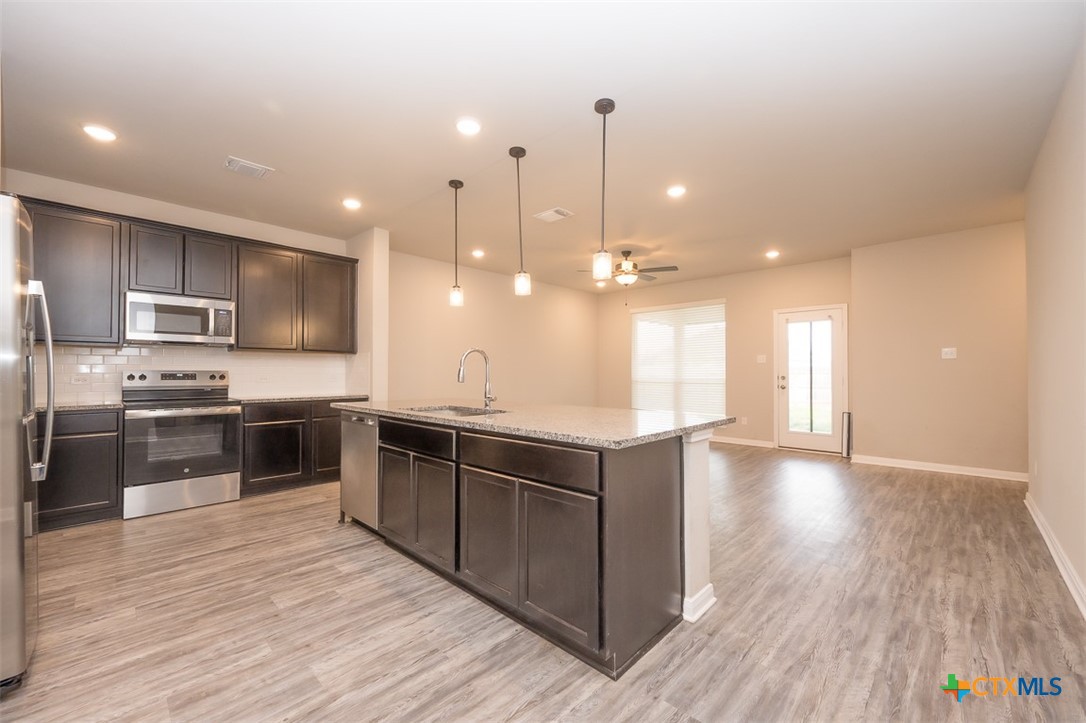 113 Lazy Lizzy Road Jarrell, TX 76537 - Photo 5 of 29 a large kitchen with stainless steel appliances kitchen island a large counter top and a wooden floors