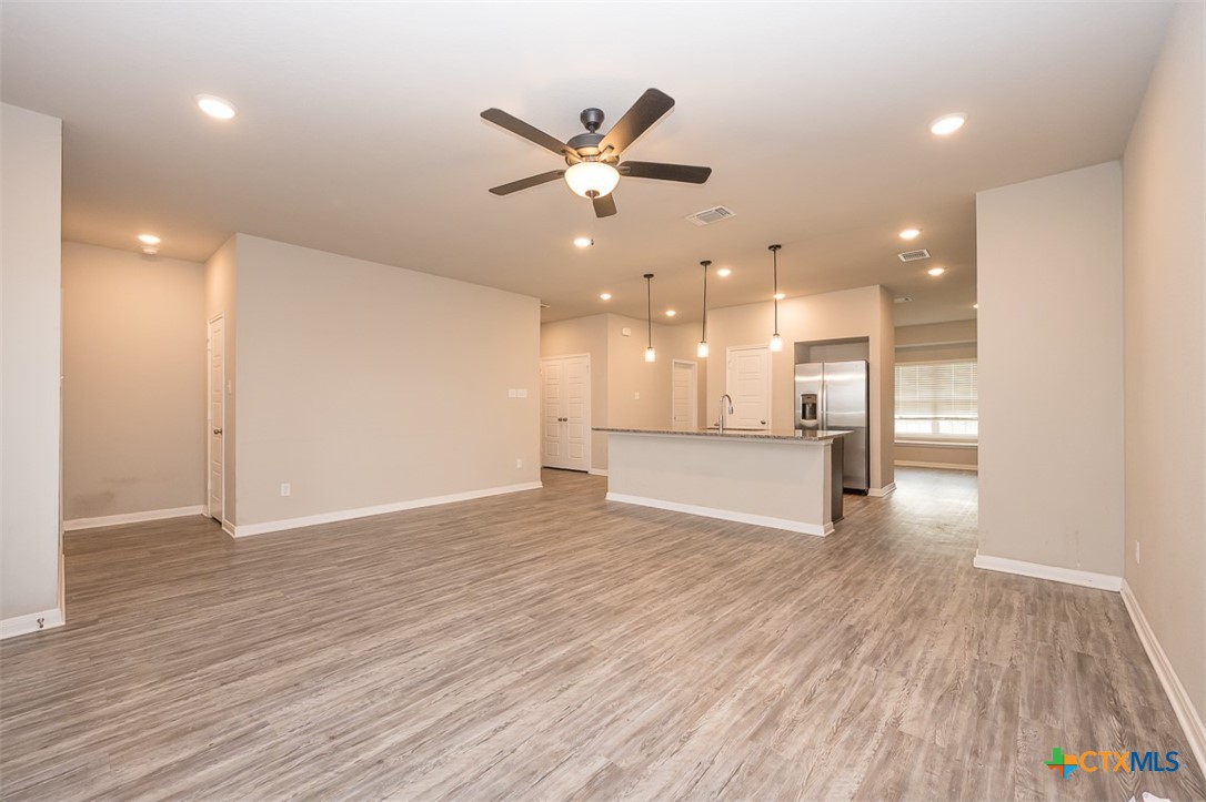 113 Lazy Lizzy Road Jarrell, TX 76537 - Photo 10 of 29 a view of an empty room with wooden floor and a ceiling fan