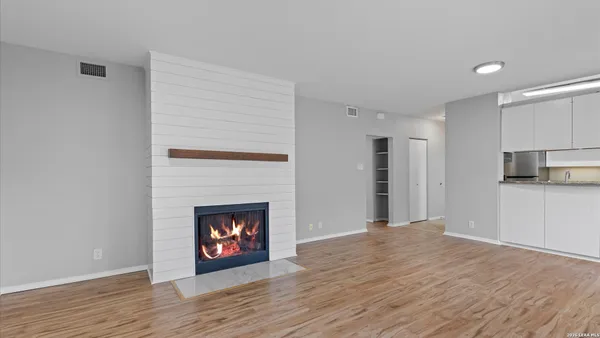a view of an empty room with wooden floor fireplace and a window