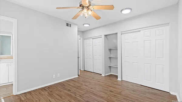 an empty room with wooden floor and a ceiling fan