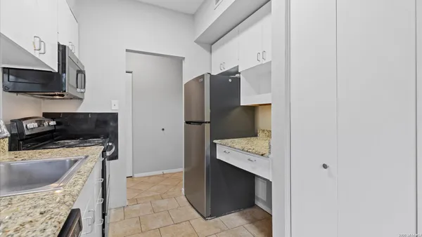 a kitchen with stainless steel appliances a stove a refrigerator a sink a counter space and cabinets