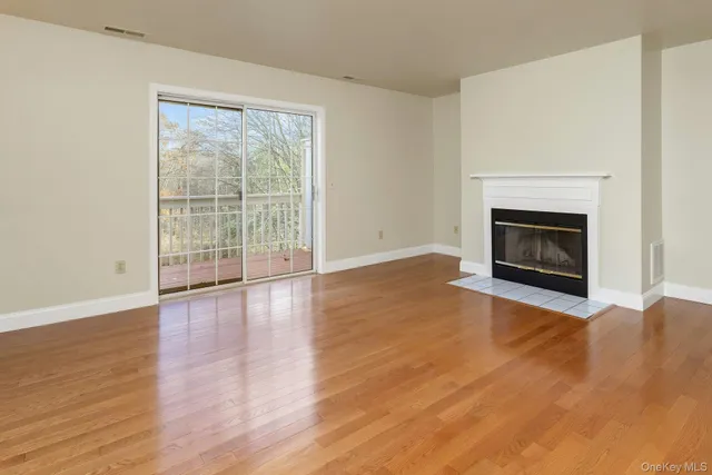 a view of an empty room with wooden floor and a fireplace