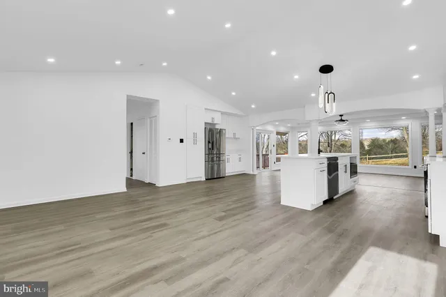 a view of a kitchen with kitchen island wooden floors appliances and a fireplace