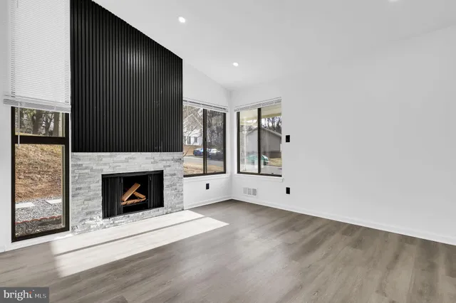 a view of an empty room with wooden floor fireplace and a window