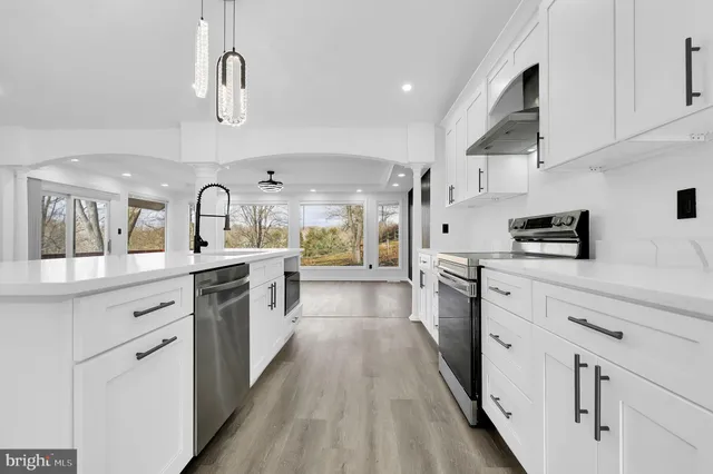 a large kitchen with stainless steel appliances sink a stove and cabinets