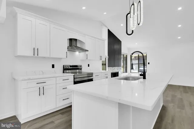 a kitchen with stainless steel appliances a sink a stove a refrigerator cabinets and living room view