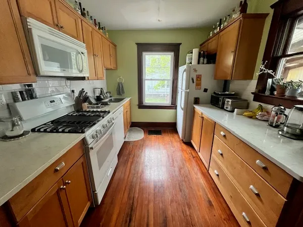 a kitchen with stainless steel appliances a sink wooden floor and cabinets