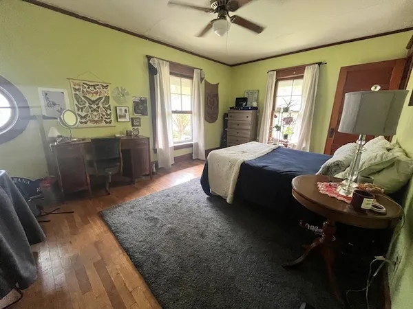 a spacious bedroom with a bed and wooden floor