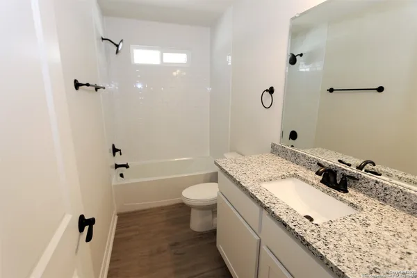 a bathroom with a granite countertop sink a toilet a mirror and shower
