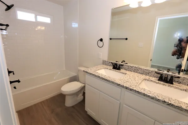 a bathroom with a granite countertop sink a toilet a mirror and bathtub
