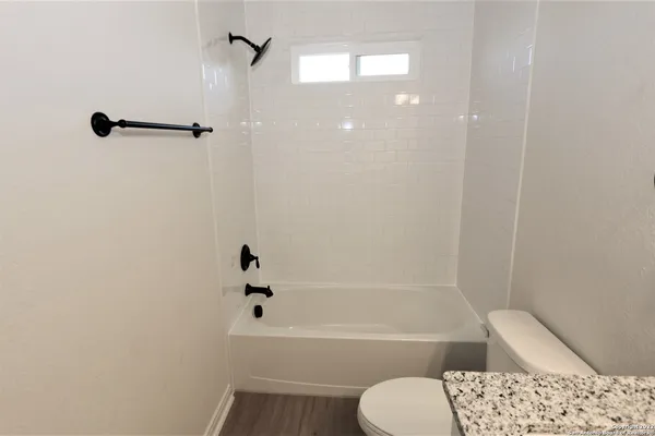 a bathroom with a bathtub shower sink vanity and toilet