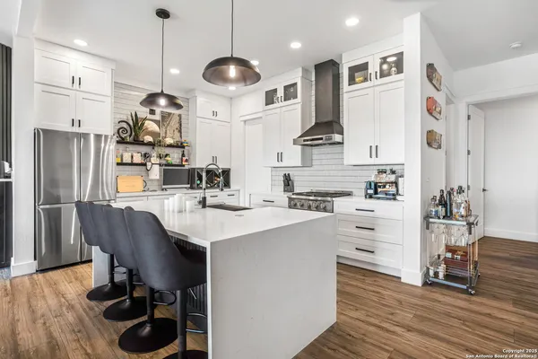 a large kitchen with stainless steel appliances a stove a sink dishwasher and a refrigerator with wooden floor