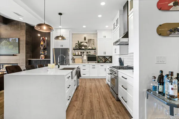 a kitchen with stainless steel appliances kitchen island granite countertop a stove a refrigerator and a wooden floors