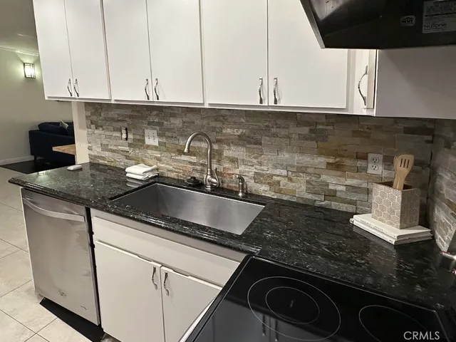 a kitchen with granite countertop white cabinets and a sink
