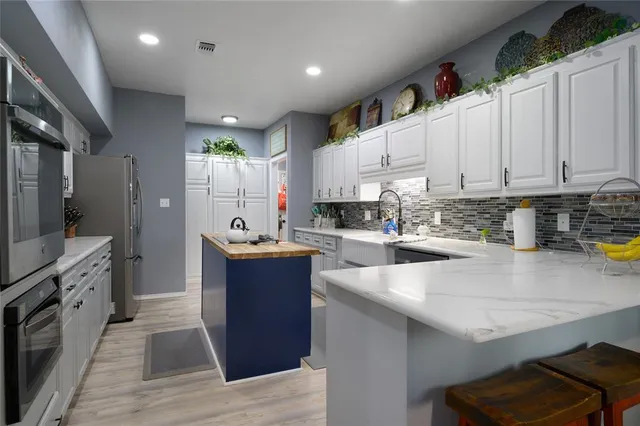 a large kitchen with stainless steel appliances granite countertop a stove refrigerator and a sink