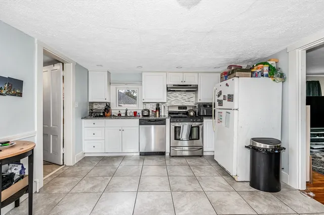 a kitchen with a refrigerator and white cabinets