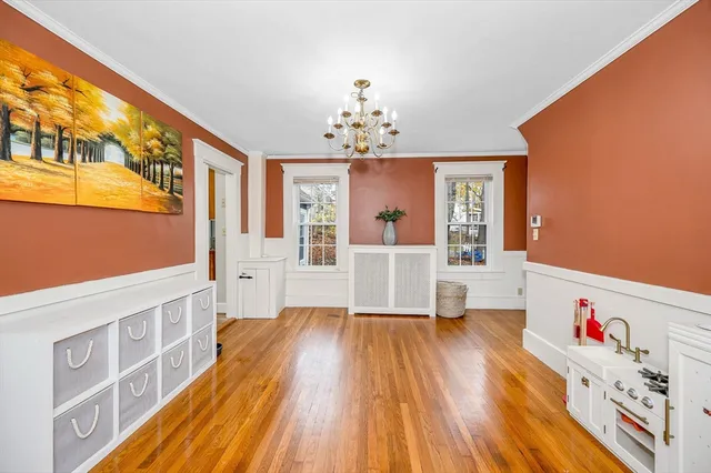 a living room with a couch wooden floor and a dining table
