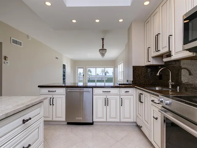 a kitchen with granite countertop white cabinets and white appliances