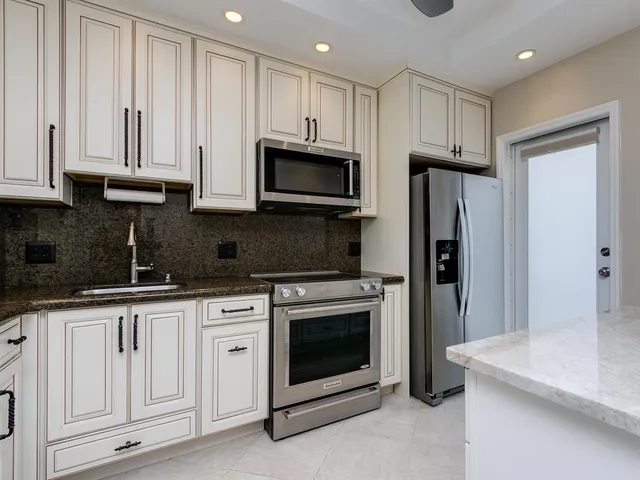 a kitchen with granite countertop white cabinets and stainless steel appliances