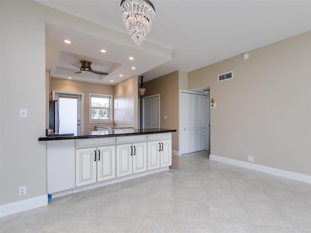 750 North Ocean Boulevard, Unit 210 Pompano Beach, FL 33062 - Photo 47 of 57 a large white kitchen with a sink and chandelier