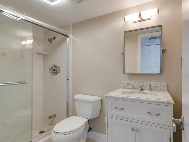 a bathroom with a granite countertop sink toilet a mirror a vanity and shower