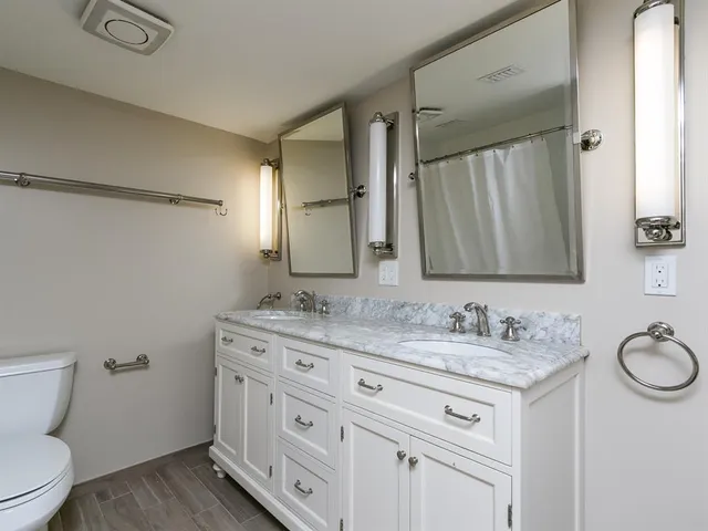 a bathroom with a granite countertop sink toilet and a mirror