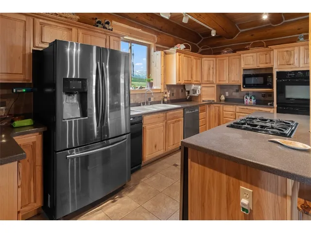 a kitchen with stainless steel appliances kitchen island granite countertop a refrigerator and a sink