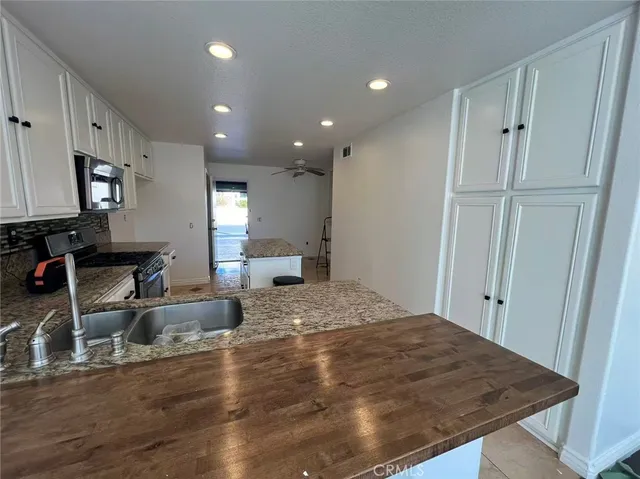 a room with kitchen island granite countertop wooden cabinets a sink and a refrigerator
