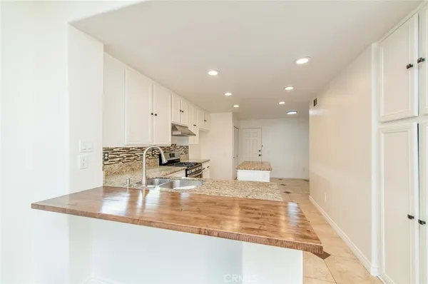 a view of a kitchen with kitchen island a sink stainless steel appliances and living room view