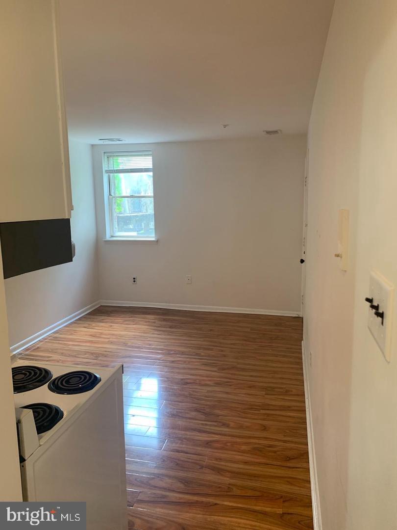 1018 Pine Street, Unit 2F Philadelphia, PA 19107 - Photo 6 of 12 a view of an empty room with wooden floor and a window