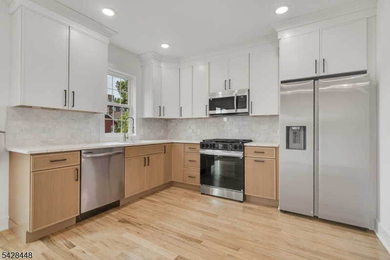 196 Taylor Street Orange, NJ 07050 - Photo 21 of 31 a kitchen with kitchen island granite countertop a sink cabinets stainless steel appliances and wooden floor