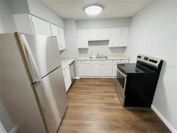 a kitchen with a refrigerator a stove top oven and white cabinets