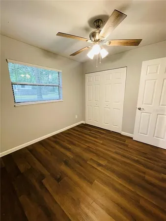 an empty room with wooden floor fan and windows