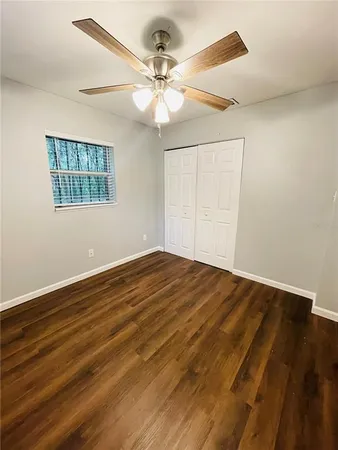 an empty room with wooden floor fan and windows