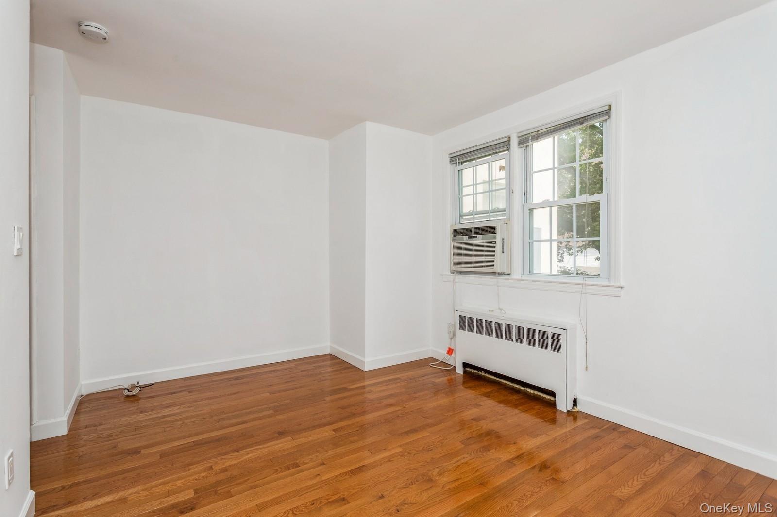 51 Cross Street, Unit 3A Yonkers, NY 10708 - Photo 13 of 17 Unfurnished room featuring radiator, a smoke detector, wood finished floors, and cooling unit
