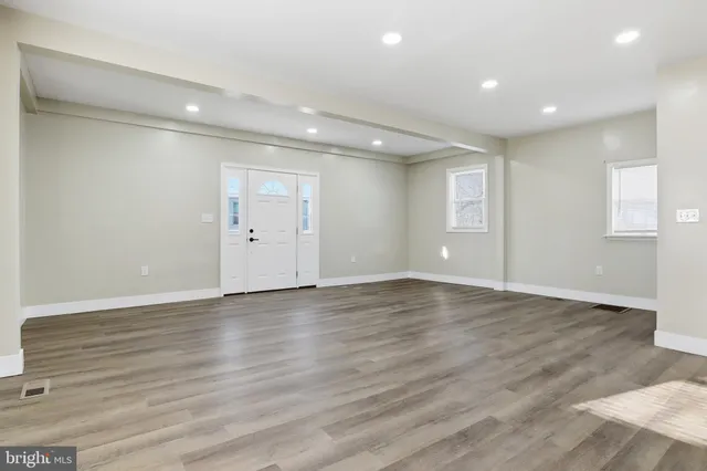an empty room with wooden floor and windows