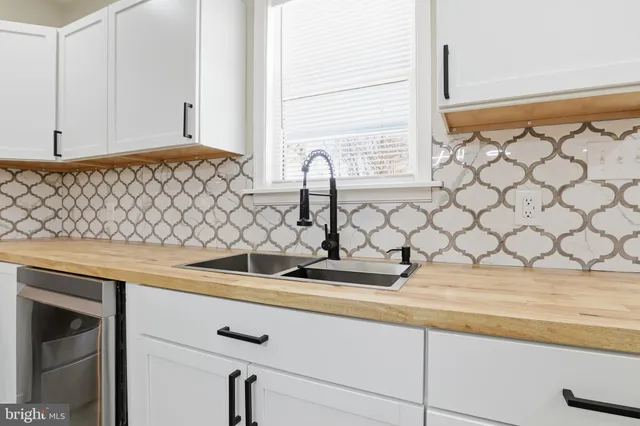 a kitchen with granite countertop a refrigerator and white cabinets
