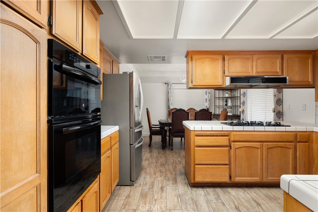 2119 Jenkins Road Bakersfield, CA 93314 - Photo 16 of 35 a kitchen with stainless steel appliances granite countertop a refrigerator a stove a sink dishwasher and wooden cabinets with wooden floor