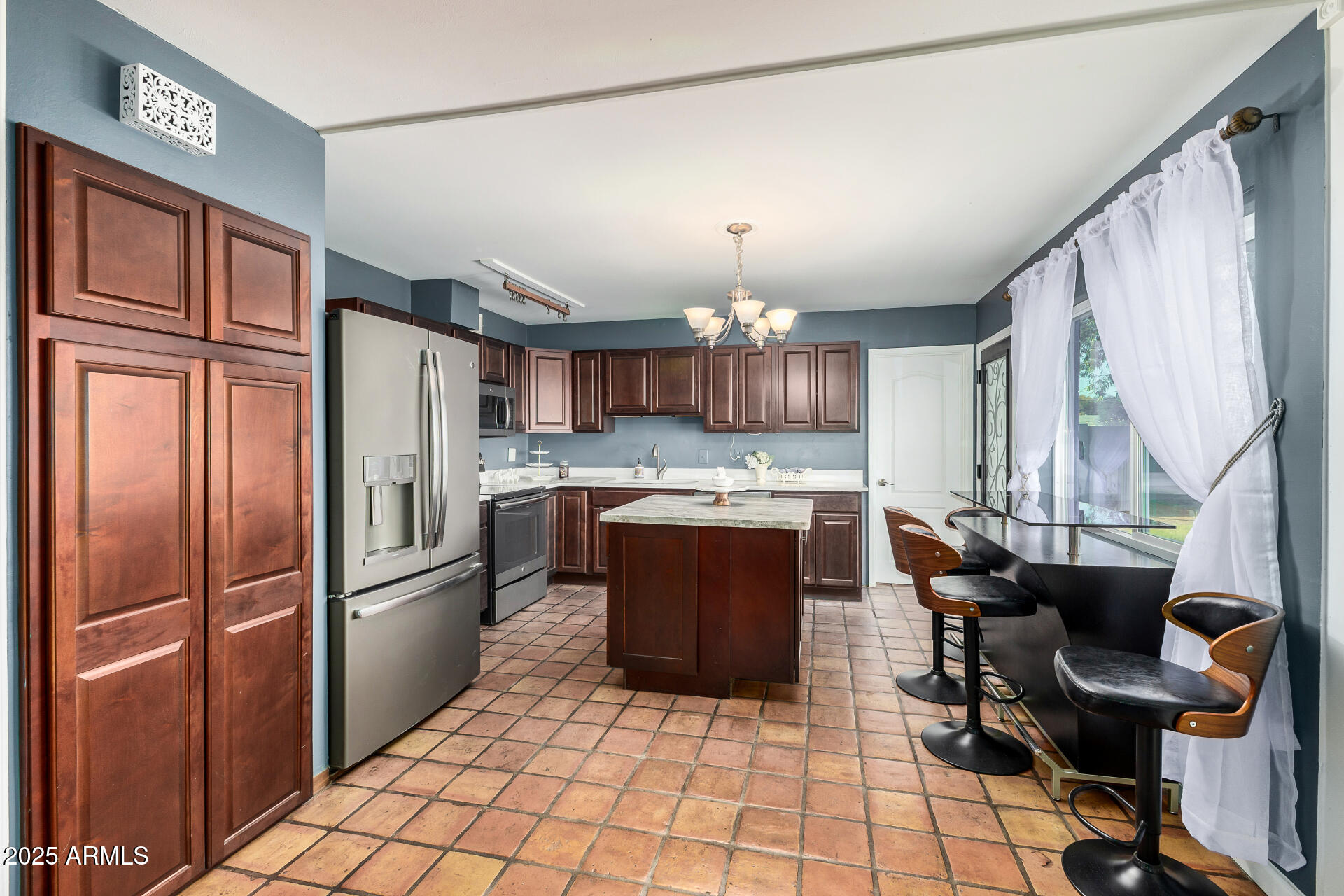 2302 West Berridge Lane Phoenix, AZ 85015 - Photo 15 of 40 a kitchen with stainless steel appliances kitchen island granite countertop a refrigerator a sink dishwasher a dining table and chairs with wooden floor