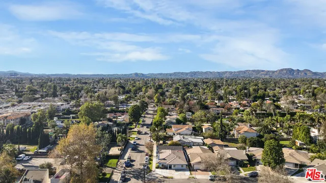 an aerial view of residential house with parking and mountain view in back