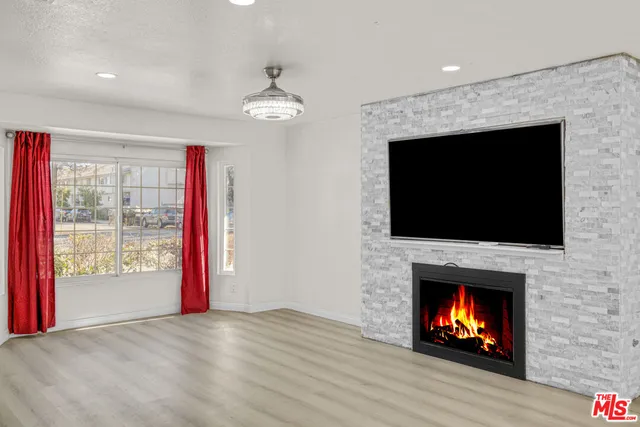 a view of an empty room with wooden floor fireplace and a window