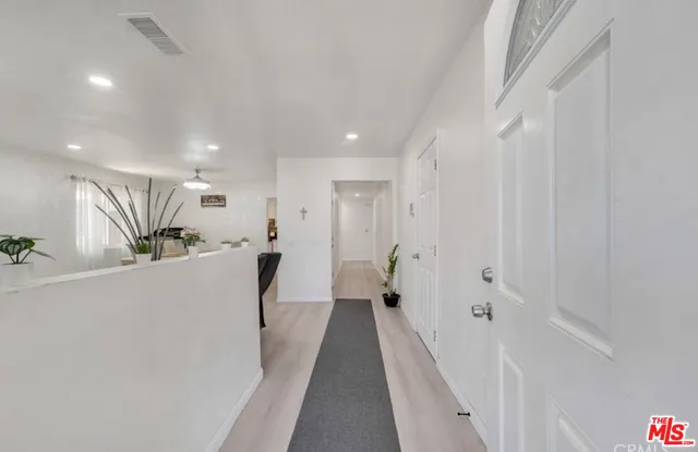 a view of a hallway with wooden floor and a living room