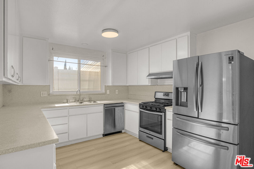 7701 Baird Avenue Reseda, CA 91335 - Photo 5 of 21 a kitchen with a refrigerator a sink and wooden floor