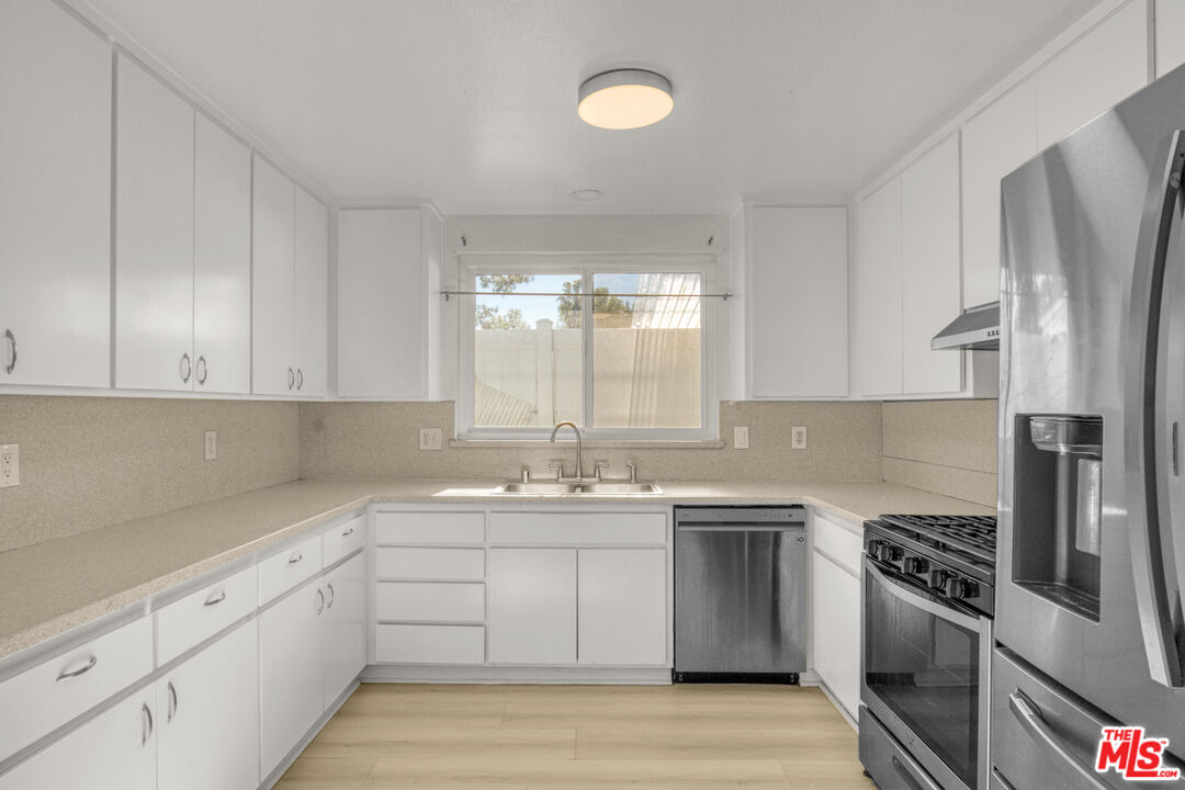 7701 Baird Avenue Reseda, CA 91335 - Photo 6 of 21 a kitchen with stainless steel appliances granite countertop a sink stove and refrigerator