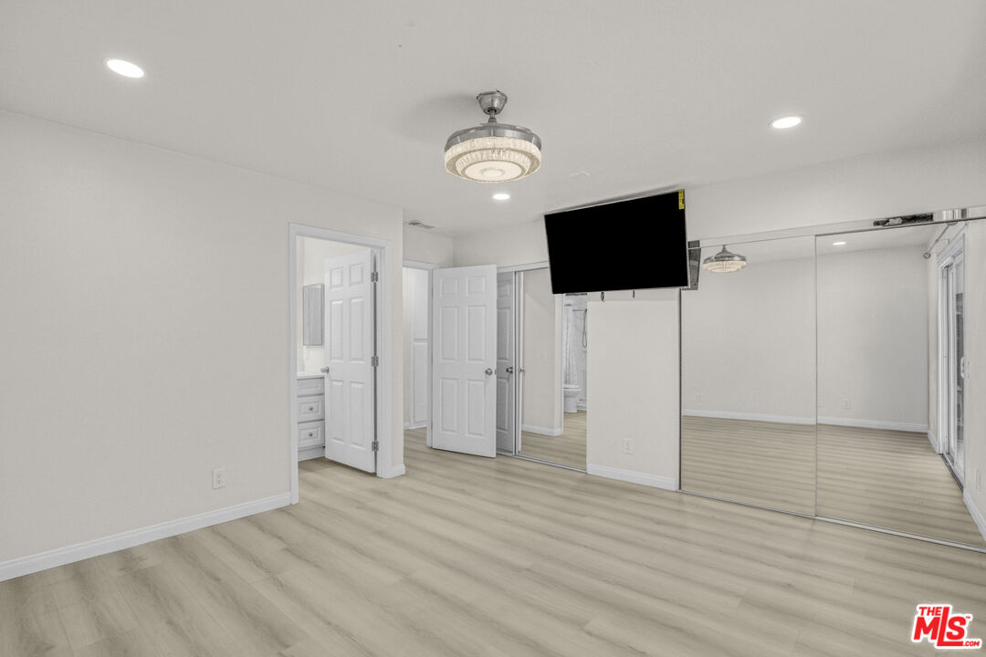 7701 Baird Avenue Reseda, CA 91335 - Photo 8 of 21 a view of an empty room with wooden floor and a ceiling fan